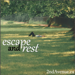 Person lying in effortless pose on the grass under leafy tree branches